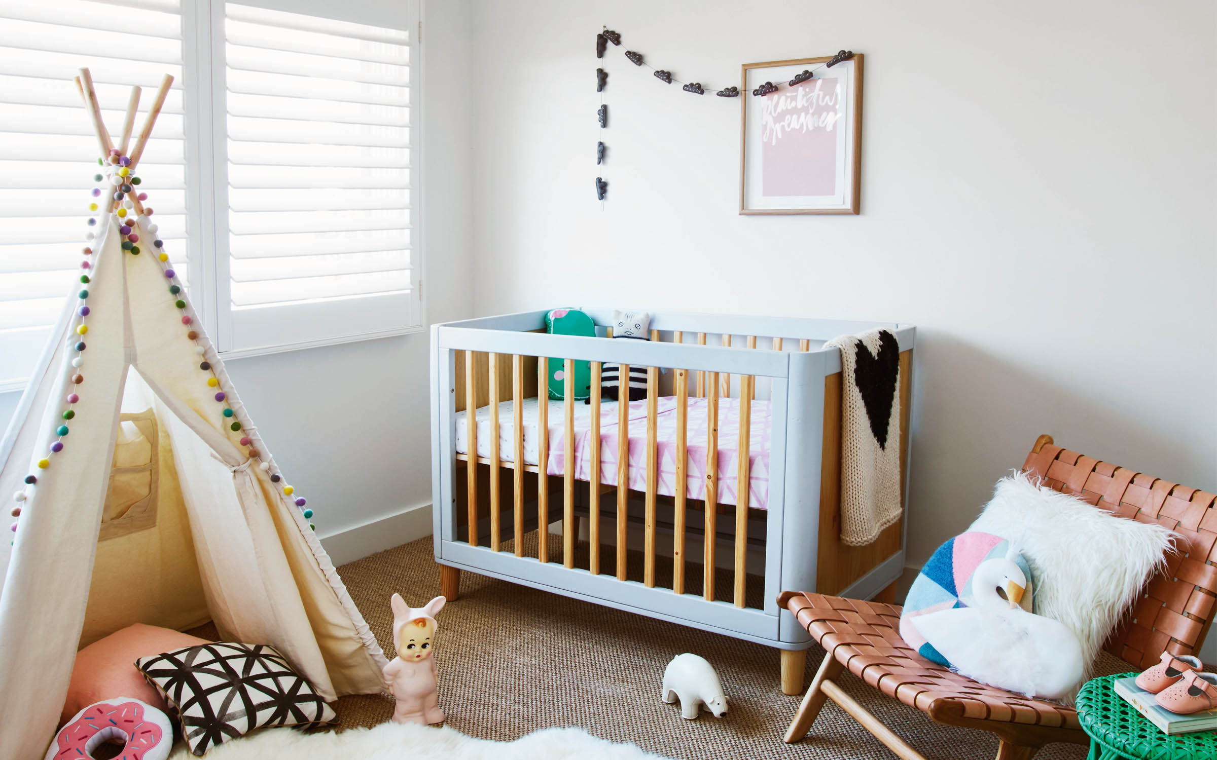 Children's room with baby cot, teepee, and mid century chair.