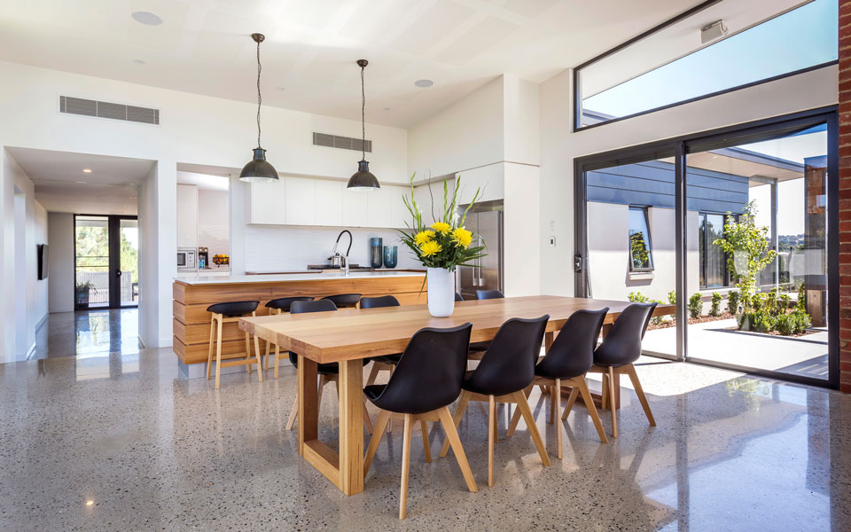 Dining room and kitchen with polished concrete floors and wooden styled furniture.