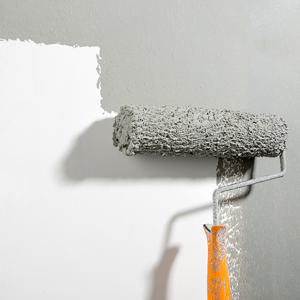 Roller brush applying grey paint to a white wall.