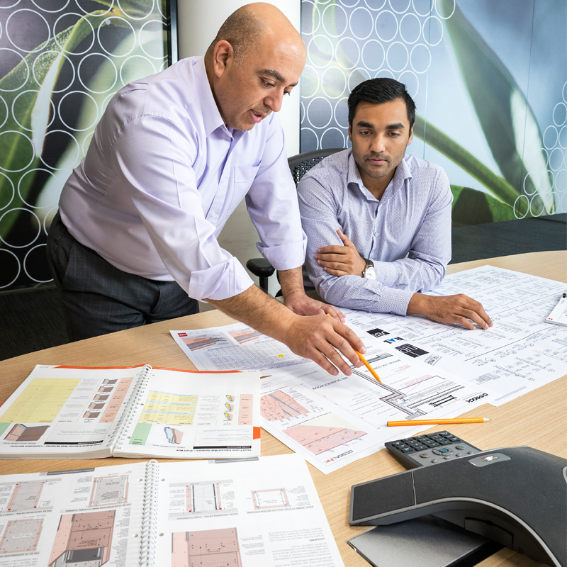 Gyprock DesignLINK team discussing a project on a table with printed material laid on top