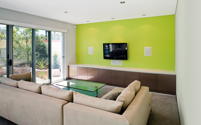 Living room area with a coloured feature wall and wall mounted television.