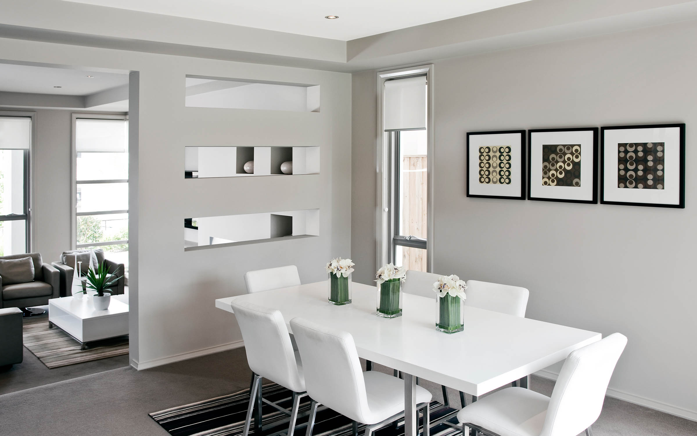 Dining table in room filled with neutral black, grey, and white tones. Artworks on walls.