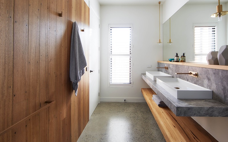 Bathroom with wooden built in features and a double vanity by a large wall mounted mirror.