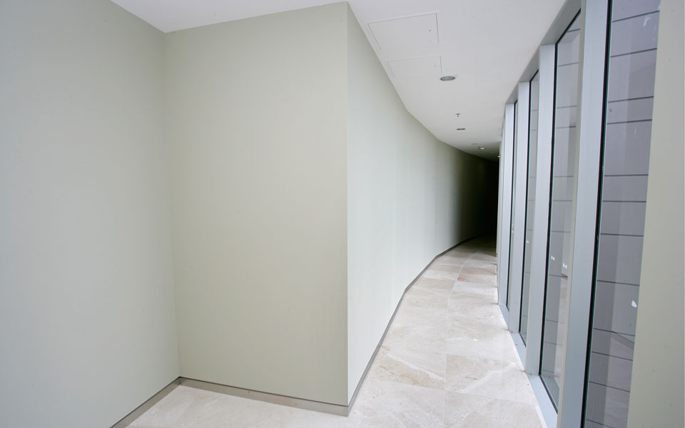 Hallway in a multi-storey apartment complex with floor to ceiling windows on one side.
