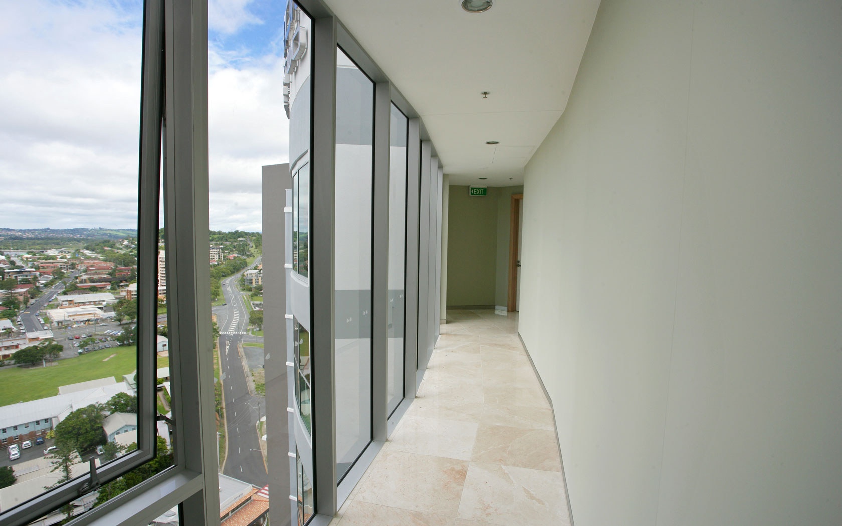 Hallway in a multi-storey apartment complex with floor to ceiling windows on one side.